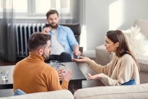 depressed young couple of man and woman speaking with psychologist on couples therapy session in modern office