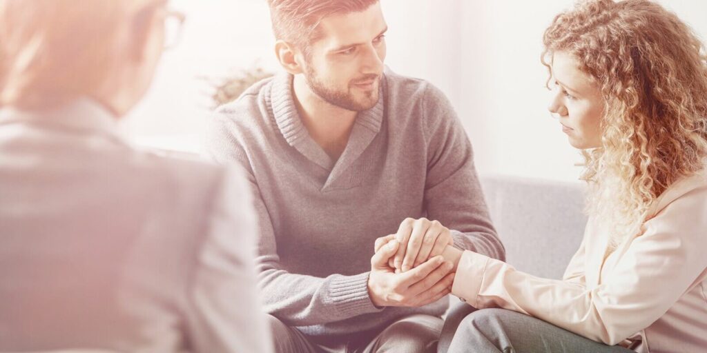 photo of handsome husband apologizing his worried wife during couple therapy with psychotherapist