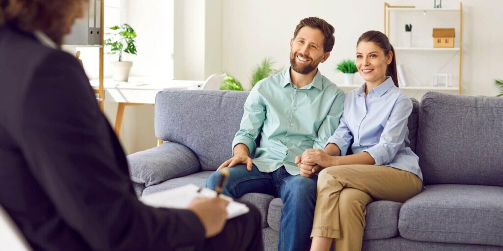 smiling young couple sitting on the couch at counselor's office