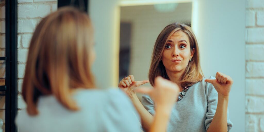 woman looking in the mirror pointing to herself at the salon