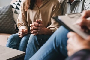 casual caucasian couple having conversation with psychologist on therapy session in room