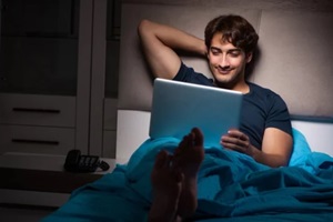 man working on laptop at night in bed