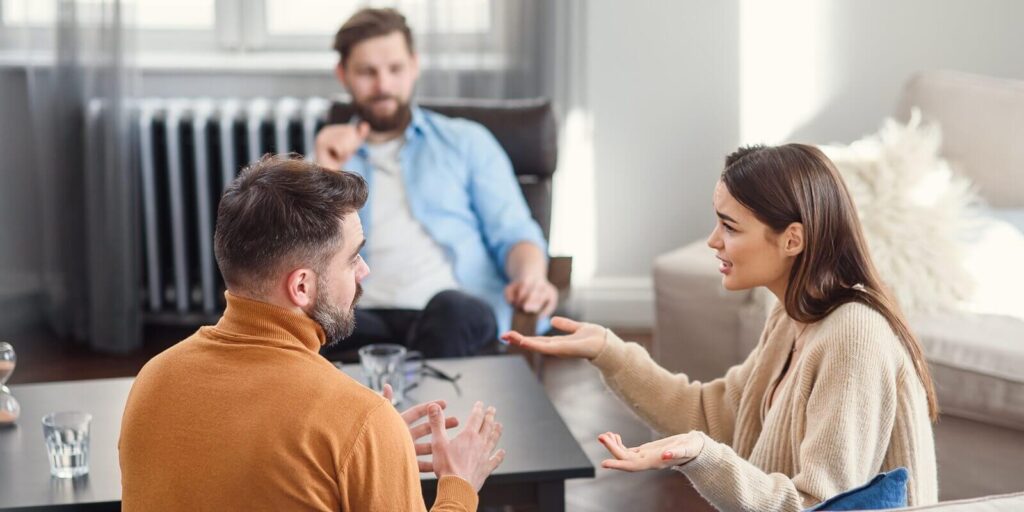 depressed young couple of man and woman speaking with psychologist on therapy session in modern office