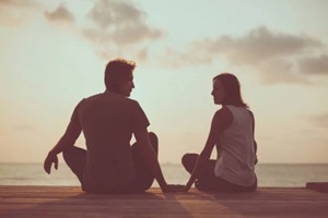 young couple is doing yoga on the sunrise background