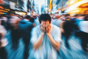 young man is overwhelmed with anxiety and fear as he covers his face in a busy