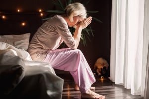 Sad Middle Aged Woman Sitting on Bed in Maryland Home
