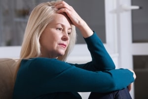 Sad Middle Aged Woman Sitting on Couch Thinking about Something