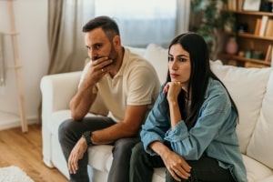 Worried Couple Sitting on Sofa Thinking about Career Transitions