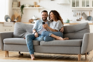 Couple Sitting on Couch Using Smartphone Together