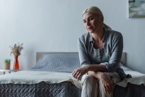 Woman Sitting on Bed Stressed Due to Menopause