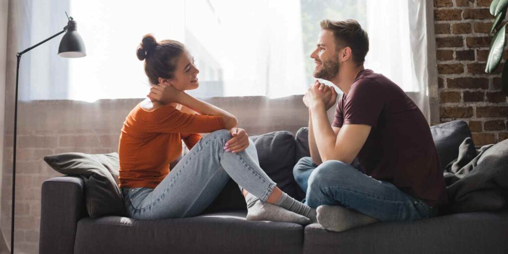 Young Couple Sitting on Sofa Talking to Each Other
