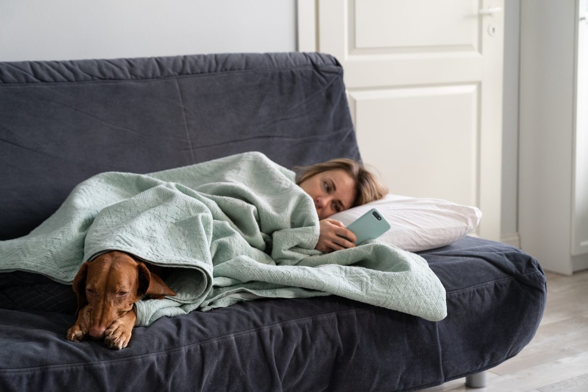individual therapy symptoms fatigue woman on couch with dog blue under blanket