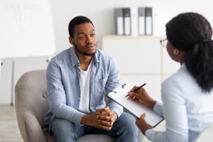 Stressed Young Man Having Session with Psychologist for Mental Health