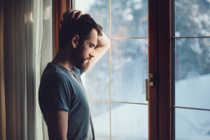 Depressed Man Standing Near Window in Winter Evening