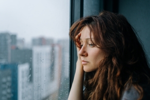 Woman with Seasonal Depression Looking out A Rainy City Window