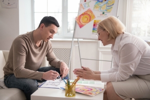 Man Drawing on Paper During Art Therapy with Psychologist