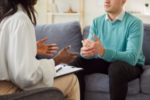 Man Sitting on Sofa Consulting with Therapist for Mental Health