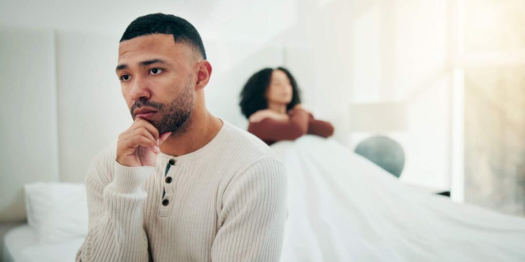 Man Sitting with Anxiety on Bed after an Argument with Partner