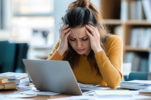 Stressed Woman Experiencing Burnout at Cluttered Office Desk
