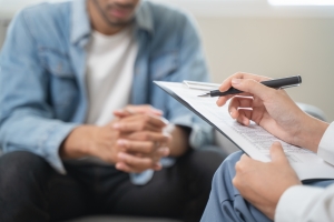 Therapist Writing Notes in Therapy Session to Make Treatment Plan for Patient