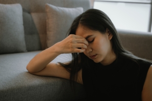 Young Woman Sitting with Grief Near Sofa