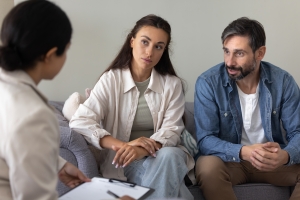 New Parents Sitting on Sofa Talking to Female Psychologist in Therapy Session