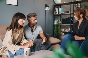 Serious Couple Having Conversation with Psychologist in Therapy Session