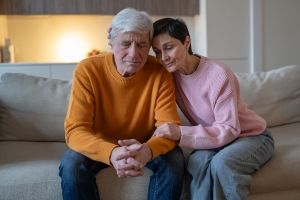 Elderly Couple Sitting on Couch Supporting Each Other During Difficult Time